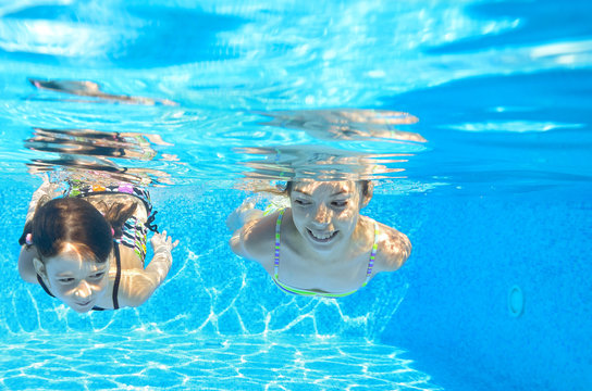 Happy kids swim underwater in pool and having fun