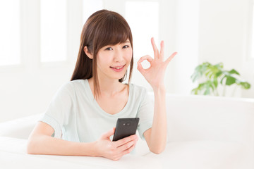 部屋でスマートフォンを見る女性