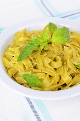 Delicious pasta with pesto on plate on table close-up