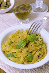 Delicious pasta with pesto on plate on table close-up