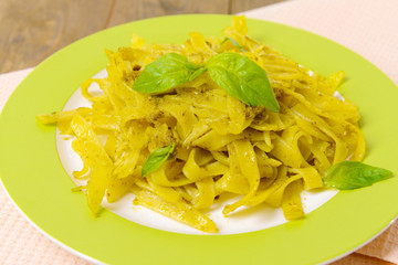 Delicious pasta with pesto on plate on table close-up