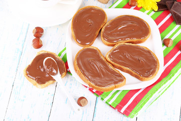 Bread with sweet chocolate hazelnut spread on plate on table