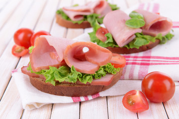 Delicious sandwiches with lettuce and ham on table close-up