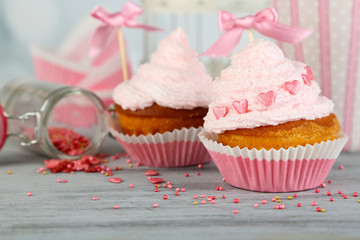 Tasty cup cakes with cream on grey wooden table