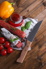 Tasty salami sausage and spices on wooden background