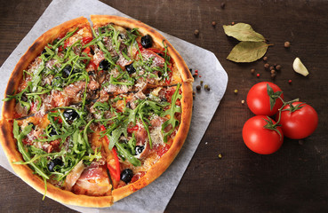 Pizza with arugula on color wooden background