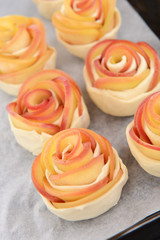 Tasty  puff pastry with apple shaped roses on pan close-up