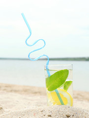 Cold drink with ice, mint and lemon on the beach