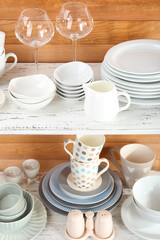 Different tableware on shelf, on wooden background