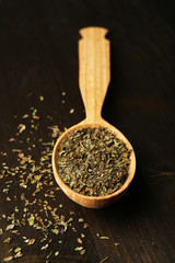 Spice greens in spoon on wooden background