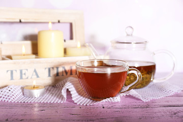 Composition with tea in cup and teapot and candles