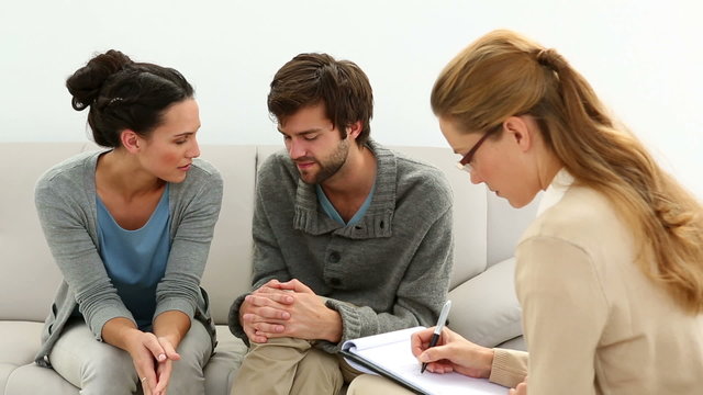 Young unhappy couple talking with their therapist