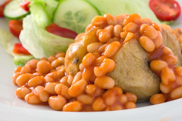 Detail of a jacket potato with baked beans and a salad.
