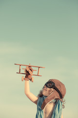 Happy child playing with toy airplane against summer sky