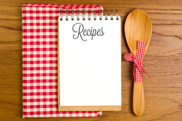 Blank note book for recipes with wooden spoon on tabletop
