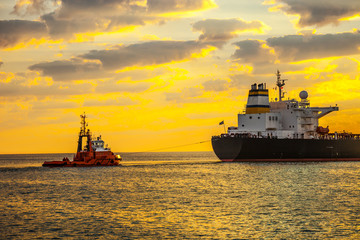 Obraz premium Tug boat pulling the tanker ship at sea.