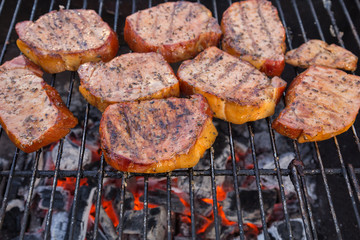 Thick seasoned pork chops cooking on the grill