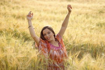 Naklejka na ściany i meble Mujer guapa lllena de felicidad en un campo de trigo