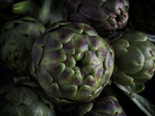 Obraz premium Freschi carciofi romani su sfondo scuro da cucinare