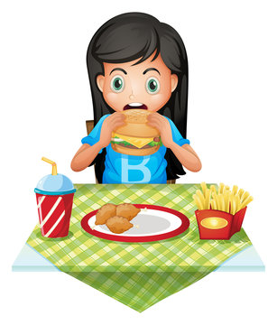 A hungry girl eating at a fastfood restaurant