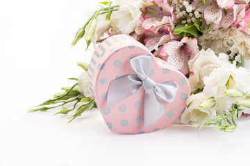 heart shaped gift against bouquet of flowers