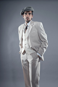 Mafia fashion man wearing white striped suit and grey cap. Studi