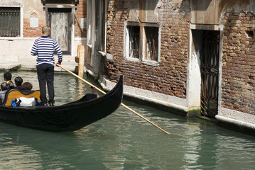 Fototapeta na wymiar Gondolier are boating tourists in the typical venetian gondola