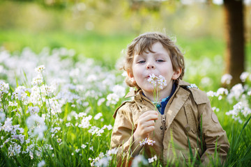 Happy little  boy in spring garden with blooming white flowers © Irina Schmidt