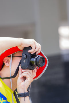man with red hat taking a photo with black camera