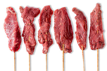 Line of raw beef kebabs on sticks