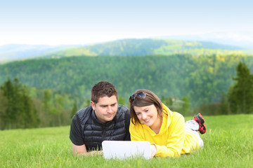 Young couple and laptop in the mountains