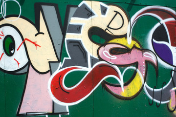 Abstract colorful graffiti on green metal fence closeup