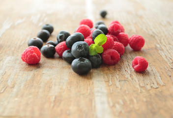 Blueberries and raspberries fruits pile on wooden table