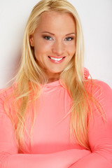 A smiling blonde in a pink hoodie