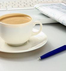 cup of coffee near the laptop and newspapers