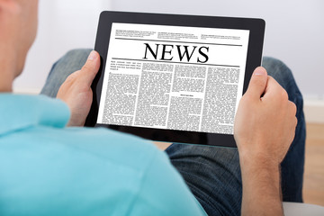Man Reading Newspaper On Digital Tablet