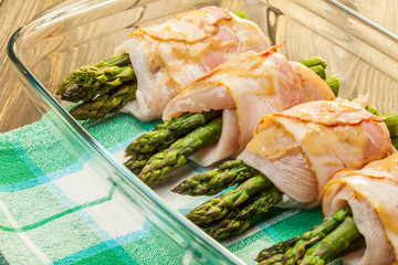 Asparagus wrapped in chicken and bacon in a baking dish