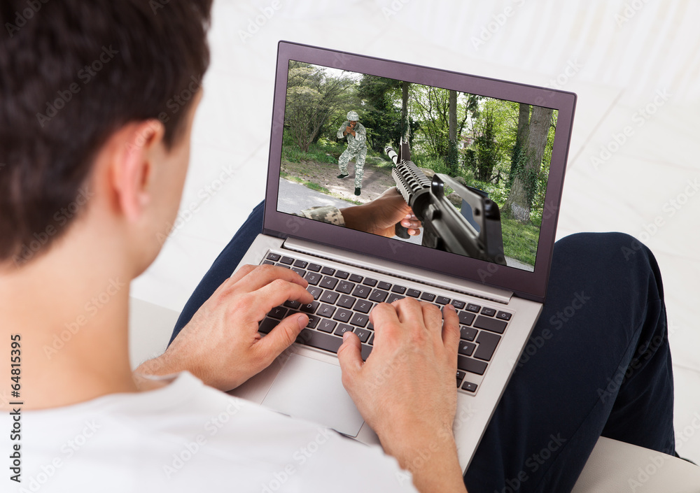 Poster man playing action game on laptop at home