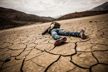 person lays on the dried ground - obrazy, fototapety, plakaty