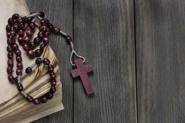 Rosary and old book on wooden table