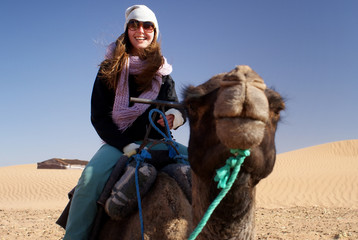 Young woman in desert riding a camel