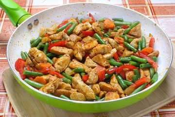 Fried chicken with vegetables in frying pan