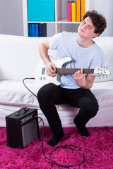 Obraz premium Boy playing electric guitar in his room