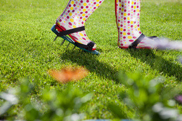 Woman wearing spiked lawn revitalizing aerating shoes