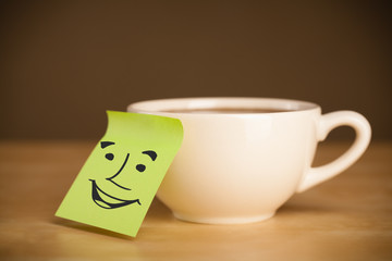 Post-it note with smiley face sticked on a cup
