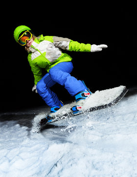 Portrait of girl jumping on snowboard at night