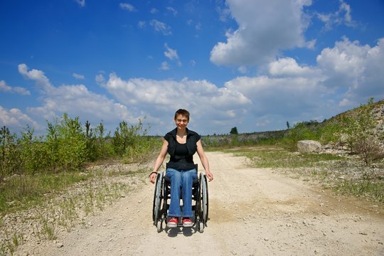 Disabled, smiling woman riding a wheelchair, path in a quarry