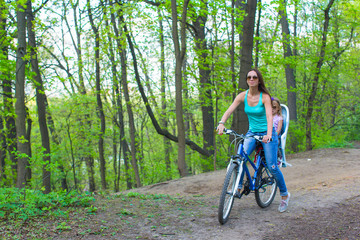 Mother and little daughter cycling bicycle at the park