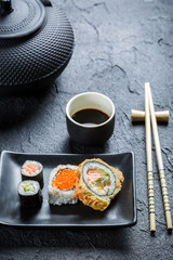 Sushi with soy sauce on the black ceramic dish