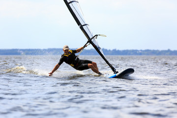 Young man surfing the wind in splashes of water